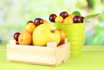 Bright summer fruits in pail and wooden box