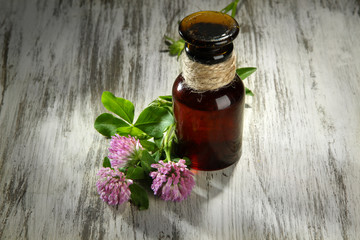 Medicine bottle with clover flowers on wooden table