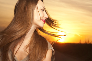 Beautiful and happy woman in front of sunrise background