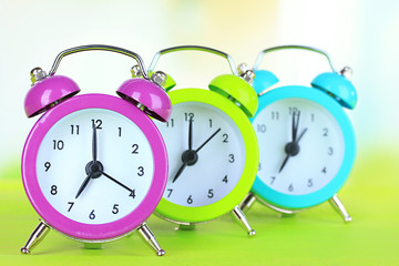 Colorful alarm clocks on table on light background