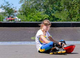 Girl with roller skates sitting lonely in the park