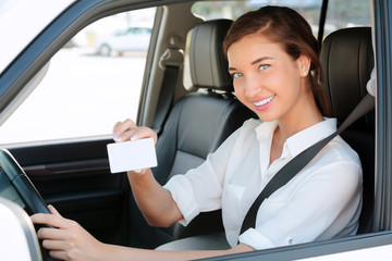 Fototapeta na wymiar girl in a car showing an empty white card for your message