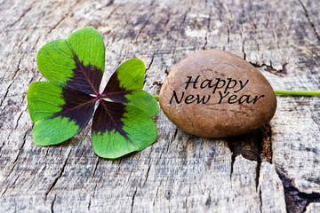 vierblättriges Kleeblatt mit Stein auf Holz, Happy New Year
