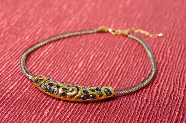 Gold Necklace with Blue Stones on Red Fabric