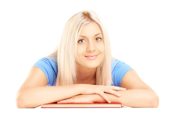 Blond female lying on a book and looking at a camera