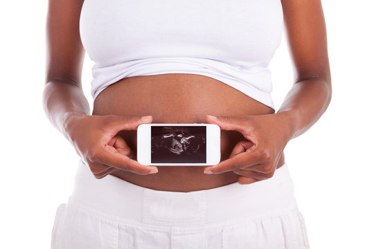 Young pregnant black woman showing an ultrasound picture of her