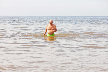 Single retired senior man enjoying the refreshment of the sea on