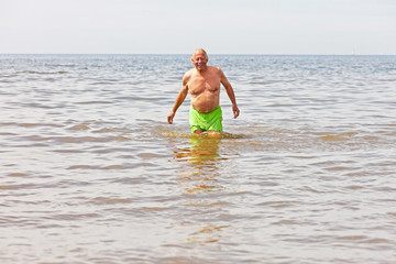Single retired senior man enjoying the refreshment of the sea on