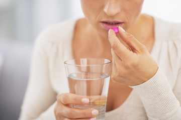 Closeup on young woman eating pill