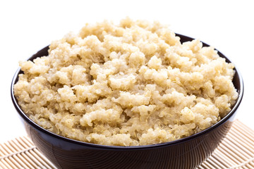 Cooked organic quinoa in brown bowl on white background