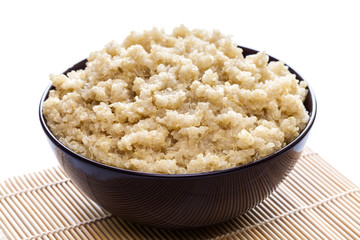 Cooked organic quinoa in brown bowl on white background