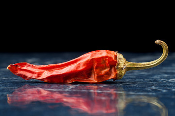 Spicy chili pepper with reflection isolated on black background