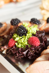 salad mix with berries and meat slaves on the silver plate