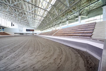 Verduisterende rolgordijnen Stadion Klein overdekt stadion met banken en met zand bekleed voor paarden