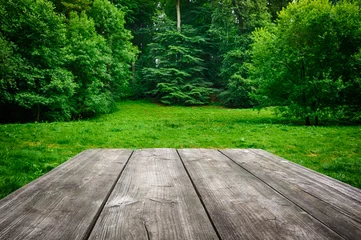 Rolgordijnen Wooden table with green nature background © Grecaud Paul