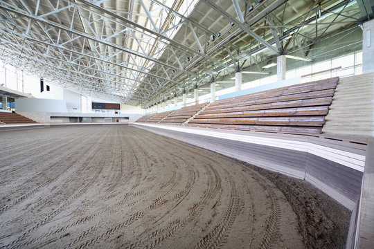 Small covered stadium with benches and sand coated for horses