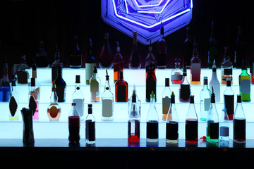 Many bottles of alcoholic drinks with blue backlight in bar