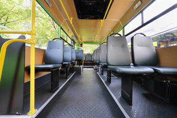 Rows of grey seats inside clear saloon of empty city bus
