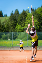 tennis players on sand court one is serving