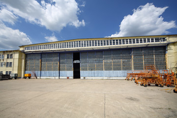 Big old battered aircraft hanger with big gate at sunny day