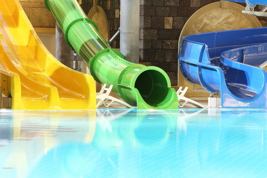 Big multi-colored water slides and pool in indoor aquapark