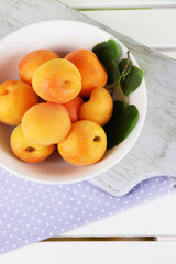 Apricots in plate on board on napkin on wooden table