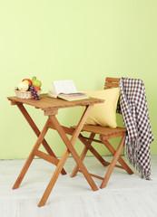 Wooden table with fruit and book on it in room