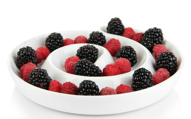 Ripe raspberries and blackberries in plate isolated on white