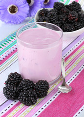 Sweet blackberries with yogurt on table close-up