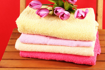 Obraz na płótnie Canvas Towels and flowers on wooden chair on red background