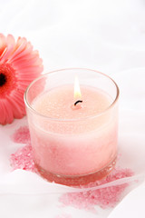 Beautiful candle with flower on white cloth, close up