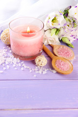 Obraz na płótnie Canvas Beautiful pink candle with flowers on purple wooden background