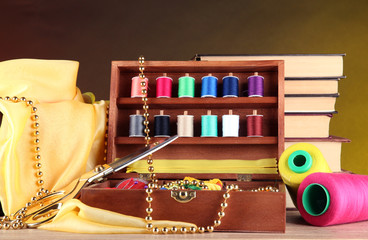 Naklejka premium Sewing kit in wooden box with books and cloth table
