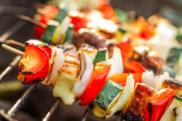 Closeup of skewers with chiken and vegetables on the grill