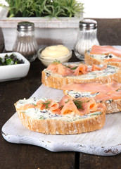 Fish sandwiches and cup of tea on cutting board on wooden table