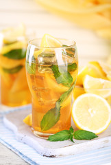 Iced tea with lemon and mint on wooden table