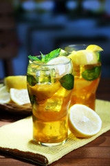 Iced tea with lemon and mint on wooden table, outdoors