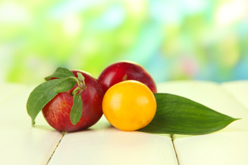 Ripe plums on wooden table on natural background