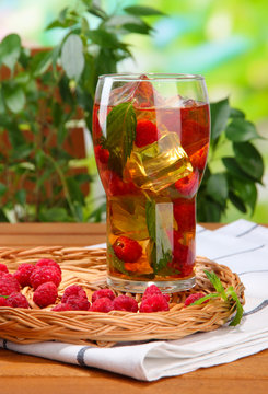 Iced tea with raspberries and mint on wooden table, outdoors