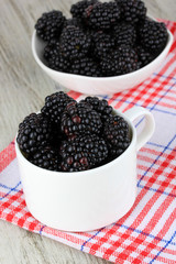 Sweet blackberries in cup on table close-up