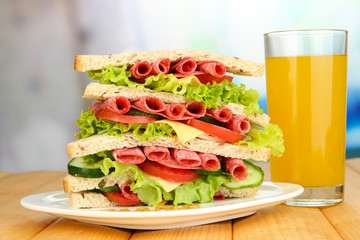 Huge sandwich on wooden table, on bright background