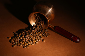 Coffee pot with coffee beans on brown background