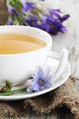 Cup of tea with chicory, on wooden background