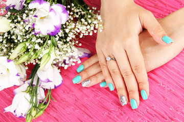 Beautiful woman hands with blue manicure near bouquet of