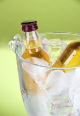 Minibar bottles in bucket with ice cubes,  on color background