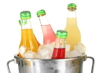 Bottles with tasty drinks in bucket with ice cubes, isolated