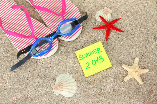 Composition with flip flops, goggles on sand background
