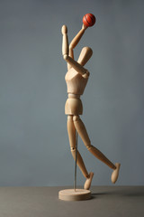 Wooden mannequin with basketball ball on grey background