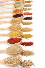 Assortment of spices in wooden spoons, isolated on white