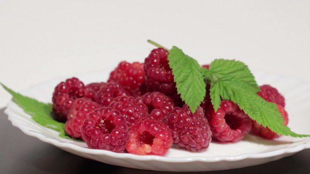 Ripe raspberries on white plate.